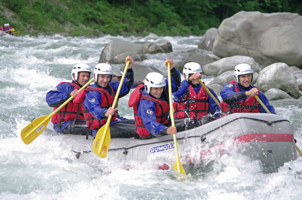 A team of people working together to steer a raft through white water rapids