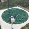 Green grating used as a sump cover in a grassy area