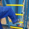 Yellow ladder rung covers on a blue ladder with a foot going to climb it