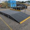 Grey mesh edging ramp with handrail on one side in the DeckSafe warehouse car park