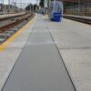 Solid top being used as trench covers at a railway platform going the length of the platform running vertically to the track