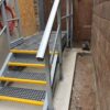 Access Staircase with grey mesh stair treads with yellow nosings and grey handrail
