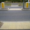 Three sets of in line tactile plates at road crossings, two on the pavement either side and one in the middle of the road
